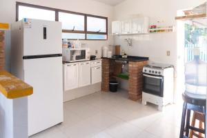 a kitchen with white appliances and a white refrigerator at Casa ampla e muito arborizada! in Prado +19 photos
