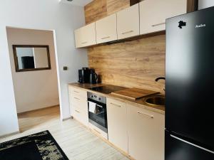a kitchen with white cabinets and a black refrigerator at Apartament Nowar in Nowa Ruda