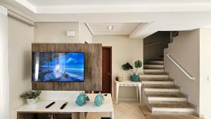 a living room with a tv on the wall at Casa em Condomínio - Churrasqueira Privativa - AC - Enseada in Guarujá