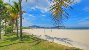 a beach with palm trees and the ocean at Casa em Condomínio - Churrasqueira Privativa - AC - Enseada in Guarujá