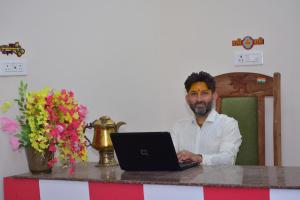 a man sitting at a counter with a laptop computer at Parmeshwari HOMESTAY in Jāmb