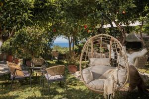 a swing in a garden with chairs and trees at Alavastros Villa Maisonettes in Vasilikos