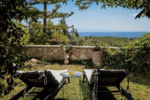 a table and two chairs in a yard with the ocean at Alavastros Villa Maisonettes in Vasilikos