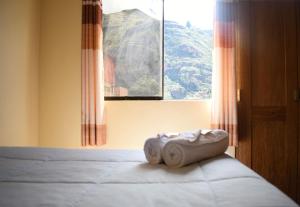 a bed with a towel on it in front of a window at Hotel Everest in Pisac