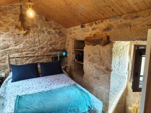 a bedroom with a bed in a stone wall at A CASIÑA DA PALMERA in Vilar