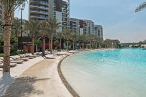 a swimming pool with lounge chairs and palm trees at Serene Haven Cozy Community Courtyard View in Dubai