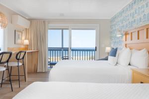 a hotel room with two beds and a balcony at Kebek 3 Oceanside Motel in Old Orchard Beach