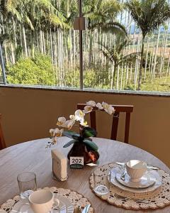 a table with plates and cups and a vase of flowers at Pousada Palmeira Imperial in Trombudo Alto