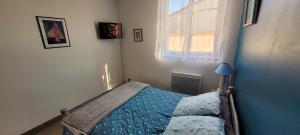 a bedroom with a bed with a blue comforter and a window at Maison pour 2 à 4 personnes avec jardin proche de la plage et des commerces ROYAN in Royan