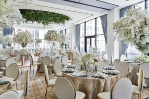 - une salle de banquet avec des tables, des chaises et des fleurs dans l'établissement The Wall Street Hotel by Suiteness, à New York