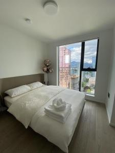 a white bed with two towels and a large window at Brand New Modern 2 BR Condo in Heart of Downtown Vancouver in Vancouver
