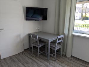 a table with two chairs and a television on a wall at Ferienwohnung Dorfaue in Lauta