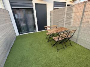 a wooden table and chairs on a patio with grass at La lyonnaise dans la jungle urbaine in Vénissieux