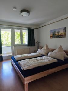 a bedroom with two beds and two windows at Ferienwohnung Bad Saarow "Am Märkischen Meer" in Bad Saarow