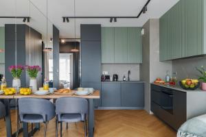 kuchnia z niebieskimi szafkami i stołem z krzesłami w obiekcie Apartament Family Green z garażem, klimatyzacją do 6 osób w Warszawie +27 zdjęć