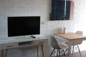 a living room with a tv and a table with chairs at Thomas Lodge Motel in Tocumwal