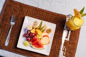 a plate of fruit on a table with a drink at Breeze Over Paddy Field Cabana in Unawatuna