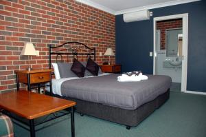 a bedroom with a bed and a brick wall at Poachers Paradise in Rutherglen