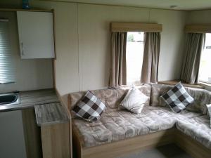 ein Sofa in einem Zimmer mit Fenster in der Unterkunft Kingfisher Horizon Elm 6 Berth Panel heated close to site shop in Ingoldmells