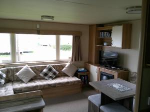 ein Wohnzimmer mit Sofa und Tisch in der Unterkunft Kingfisher Horizon Elm 6 Berth Panel heated close to site shop in Ingoldmells