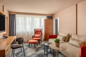 a living room with a couch and chairs and a tv at Vienna Marriott Hotel in Vienna +129 photos