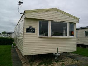 ein kleines Haus mit einem Fenster in einem Hof in der Unterkunft Kingfisher Horizon Elm 6 Berth Panel heated close to site shop in Ingoldmells