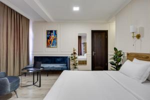 una camera da letto con un grande letto bianco e una sedia di Regraph Hotel a Tbilisi City