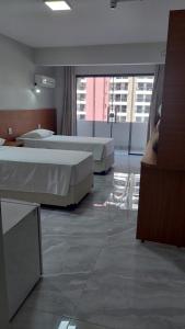 two beds in a hotel room with two chairs at Happy Hotel Garvey Park in Brasília