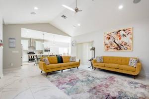 a living room with two yellow couches and a kitchen at Private Bedroom with Bath & Pool Access in Peaceful Port Saint Lucie in Port Saint Lucie