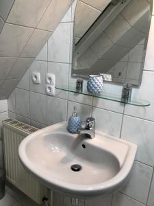 a white sink in a bathroom with a mirror at ruhige aber zentral gelegene Ferienwohnung im Obergeschoss in Dornum