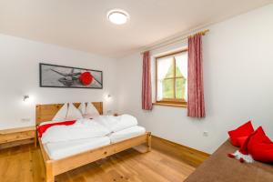 a bedroom with a bed with white sheets and red pillows at Tratterhof Apartments in Vallarga