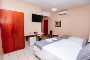 a hotel room with a bed and a desk and a tv at Hotel Fazenda Mato Grosso in Cuiabá