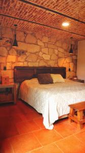 una camera da letto con un muro in pietra con un letto di ALOLAH en el corazón del bosque, Huasca a La Venta