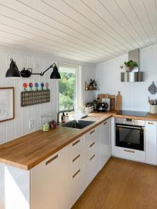 une cuisine avec des armoires blanches et un comptoir en bois dans l'établissement True Atmosphere With Sea View And Beach, à Idestrup