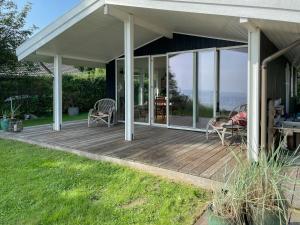 a deck with chairs and tables on a house at True Atmosphere With Sea View And Beach in Idestrup