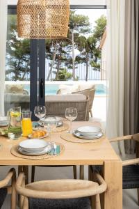 Una mesa de madera con platos y copas de vino encima. en Villa Vartal, en Ivan Dolac