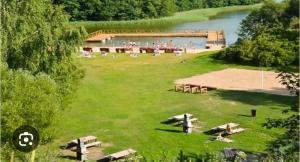 a large field with picnic tables and a lake at Mieszkanie do wynajęcia w Centrum in Olecko