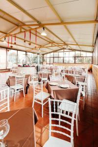 a restaurant with tables and white chairs and windows at Il Casale Colle San Pietro in San Pietro