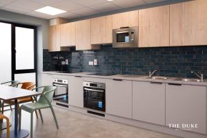 a kitchen with white cabinets and a table and a microwave at The Duke Maynooth in Maynooth