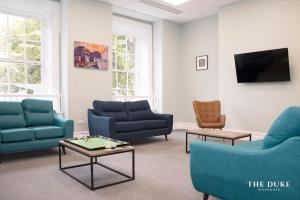 a living room with blue couches and a tv at The Duke Maynooth in Maynooth