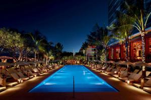 a swimming pool with lounge chairs and a hotel at The Miami Beach EDITION in Miami Beach