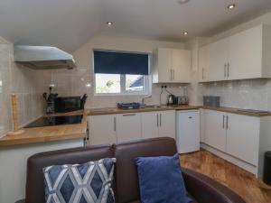 a living room with a couch and a kitchen at Eve's Attic in Bowness-on-Windermere
