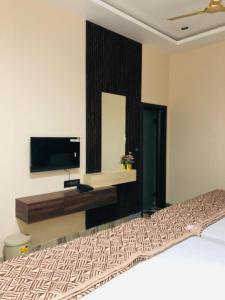 a bedroom with a bed and a flat screen tv at Hotel Ram Ghar - Near Mathura Junction Railway Station in Mathura