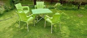 吉塔尔WindyCrest Inn的一群绿色的椅子和一张桌子在草地上
