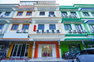 a building with colorful fronts on a street at Hotel O Rungkut Near Its Surabaya Formerly Ace Business Hotel in Surabaya