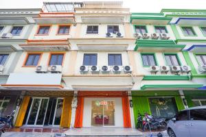 a large building with colorful fronts on a street at Hotel O Rungkut Near Its Surabaya Formerly Ace Business Hotel in Surabaya