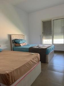 a bedroom with two beds and two windows at Amwaji in El Alamein