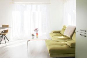 Una sala de estar con un sofá verde y una mesa. en Apartment with balcony at the gates of Paris, en Bagnolet