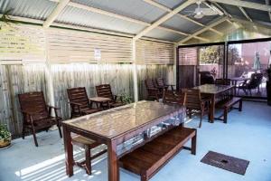 eine Terrasse mit Tischen, Stühlen und einem Zaun in der Unterkunft Garden City Motor Inn in Brisbane