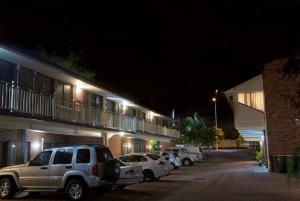 eine Reihe von Autos, die nachts auf einem Parkplatz geparkt sind in der Unterkunft Garden City Motor Inn in Brisbane